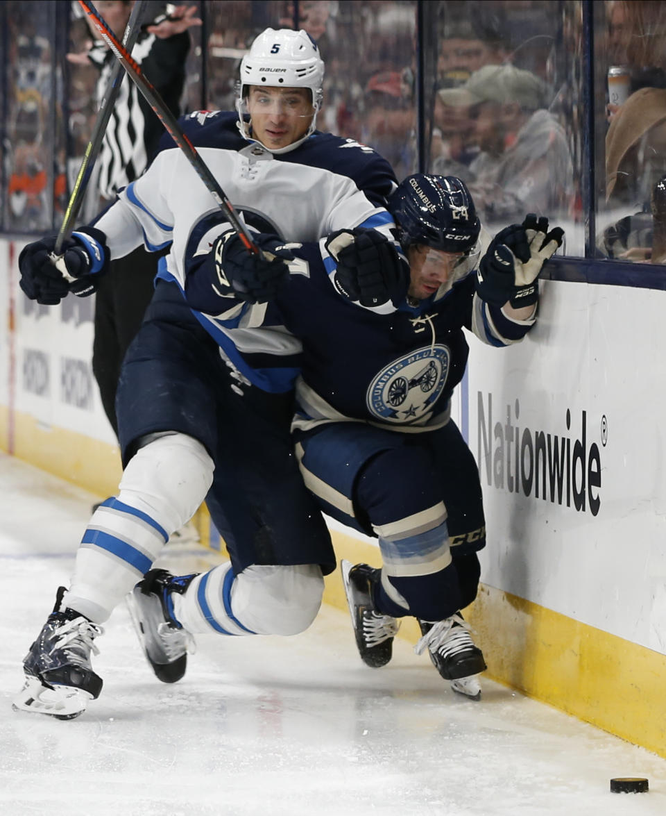 Winnipeg Jets' Luca Sbisa, left, of Italy, checks Columbus Blue Jackets' Nathan Gerbe during the second period of an NHL hockey game Wednesday, Jan. 22, 2020, in Columbus, Ohio. (AP Photo/Jay LaPrete)