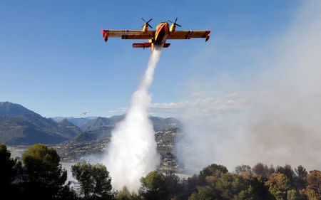 A Canadair firefighting aircraft drops water on a wildfire which burns a forest in Carros, near Nice, France, July 24, 2017. REUTERS/Eric Gaillard