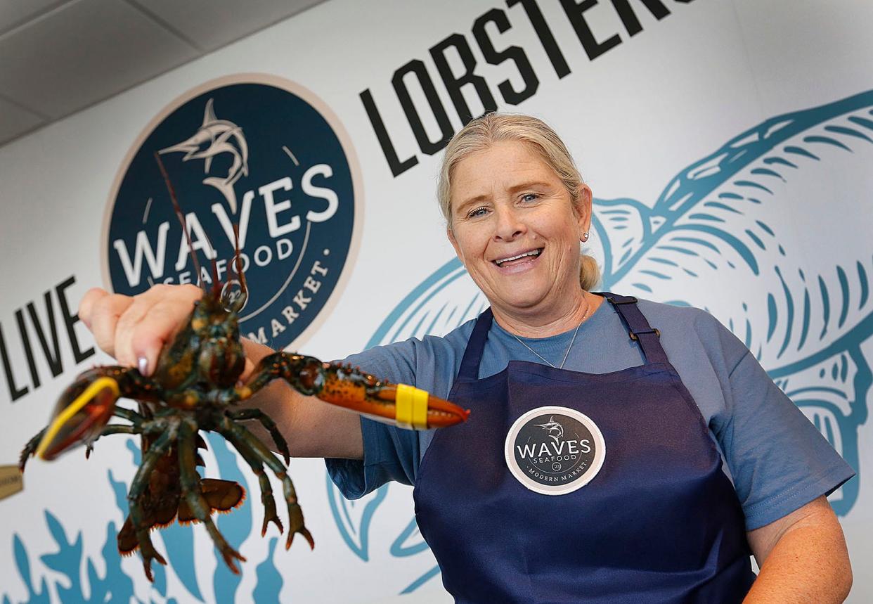 Waves Seafood employee Jennifer Briscoe, of Weymouth, selects a 2-pound lobster for a customer from the live lobster tank.