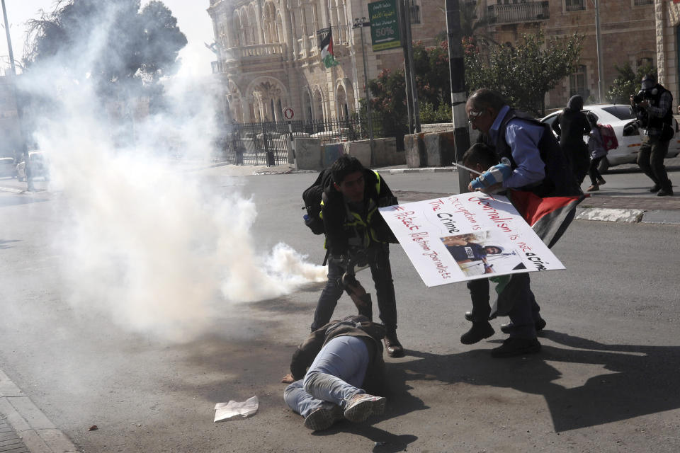 Palestinian journalists help a colleague who fell running away from tear gas and sound bombs thrown by Israeli border police during a journalist's protest in support of a 35 year-old photographer Muath Amarneh in Bethlehem, West Bank, Sunday, Nov. 17, 2019. Amarneh's relatives say he has lost vision in one eye after apparently being struck by Israeli fire while covering a demonstration in the West Bank. Israel's paramilitary border police unit says it did not target him. (AP Photo/Mahmoud Illean)