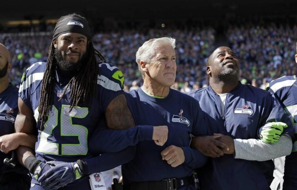 Richard Sherman (25) and coach Pete Carroll, center, are hoping to lock arms and be united more in 2017 than they were in 2016. That seems to be the clear intent behind the coach’s comments about his three-time All-Pro cornerback this week at the NFL owners meetings in Phoenix.