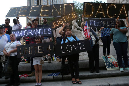 People hold signs against U.S. President Donald Trump's proposed end of the DACA program that protects immigrant children from deportation at a protest in New York City, U.S., August 30, 2017. REUTERS/Joe Penney/Files