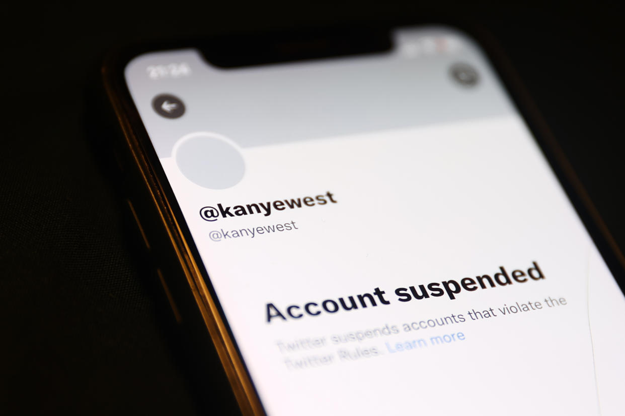 Phone screen that reads: @kanyewest, Account suspended, Twitter suspends accounts that violate the Twitter Rules. Learn more.