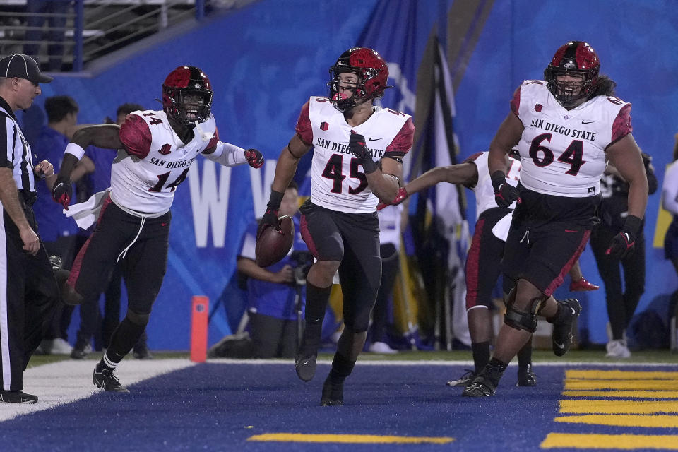 San Diego State wide receiver Jesse Matthews (45) celebrates with teammates Tyrell Shavers (14) and Chris Martinez (64) after catching a touchdown for the game winning score in double overtime in a NCAA college football game, Friday, Oct. 15, 2021, in San Jose, Calif. (AP Photo/Tony Avelar)