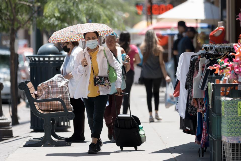 El Pasoans use umbrellas to block the hot sun while shopping in Downtown El Paso on Tuesday, May 17, 2022.