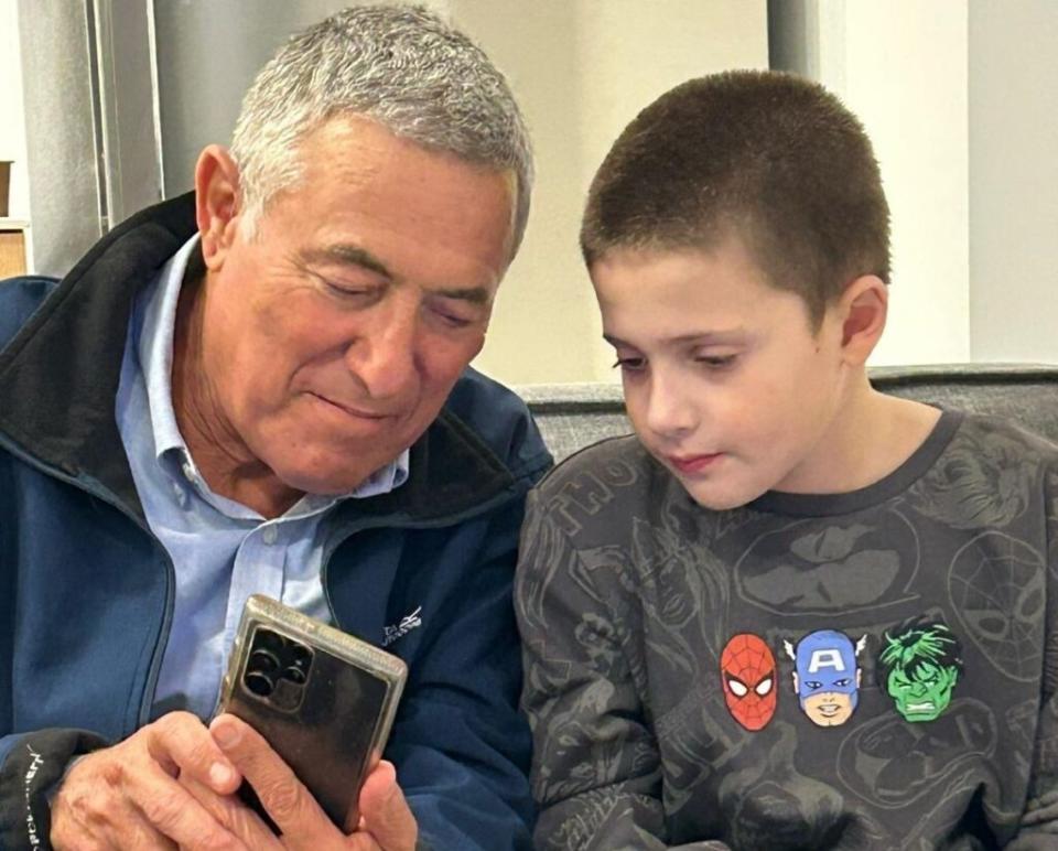 Doron Almog, chairman of the executive of the Jewish Agency for Israel, shows something on his phone to his cousin, Tal Goldstein Almog, at Schneider Children's Hospital after the boy was released from Hamas captivity in November. 
