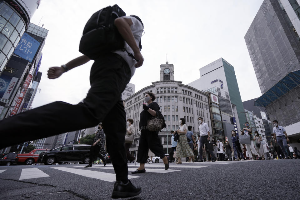 People wearing a mask against the spread of the new coronavirus walk on a pedestrian crossing in Tokyo Monday, July 20, 2020. The Japanese capital has confirmed Monday more than 160 new coronavirus cases. (AP Photo/Eugene Hoshiko)