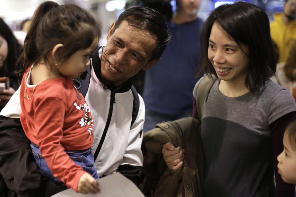 Thy Chea, of Lowell, Mass., center, originally of Cambodia, holds his daughter, left, as attorney Bethany Li, right, looks on Chea's arrival at Boston's Logan Airport, Wednesday, Feb. 26, 2020, after getting his green card reinstated last year. Chea is the fourth Cambodian refugee to be allowed back into the country after being deported, and just the first on the East Coast, according to Asian American organizations that have been fighting increased deportations of Southeast Asians under President Donald Trump. (AP Photo/Steven Senne)