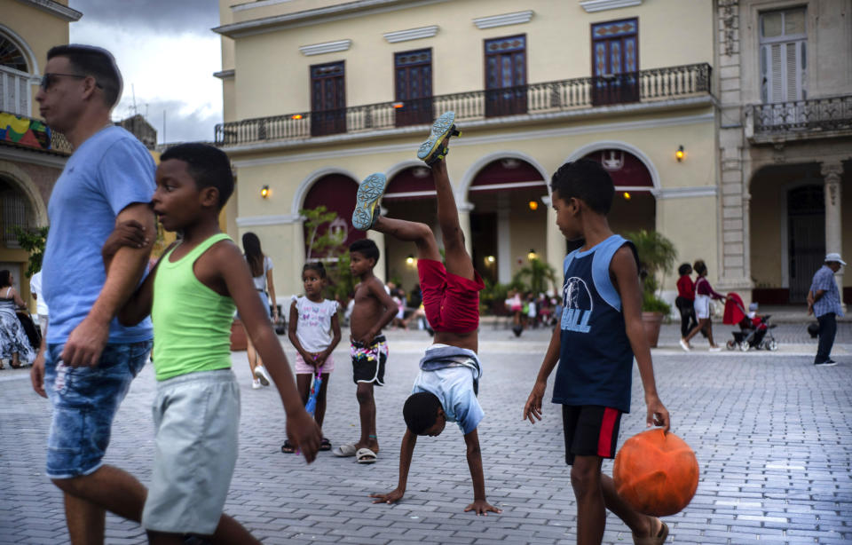 In this Nov. 10, 2019 photo, a youth does hand stands amid pedestrians in a square in Old Havana, Cuba. The city will celebrate its 500th anniversary on Nov. 16. (AP Photo/Ramon Espinosa)