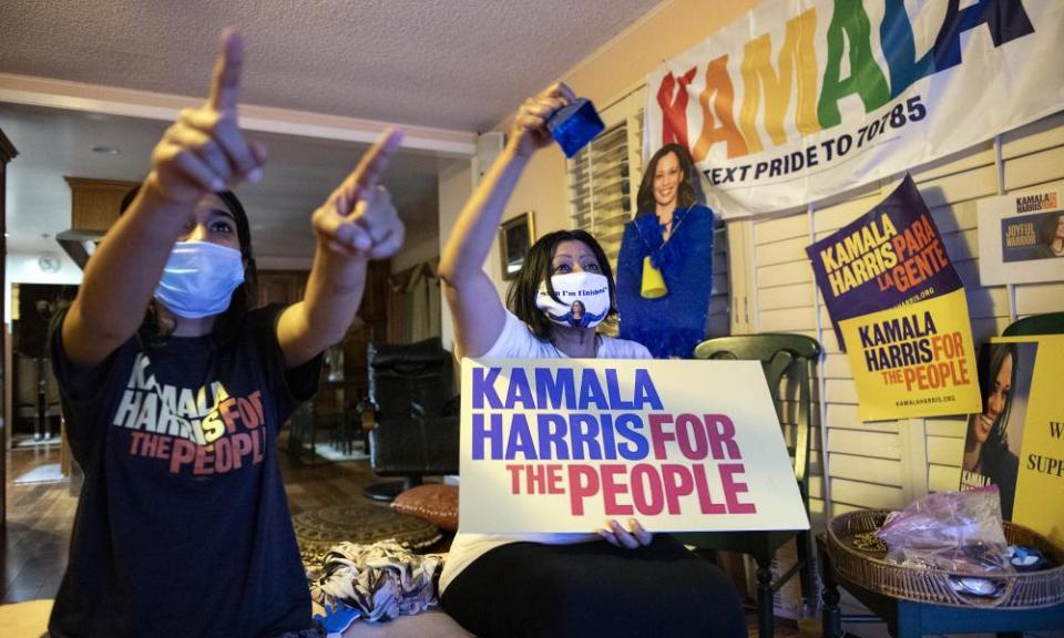 Harini Krishnan, right,  and her daughter Janani Krishnan-Jha cheering with a poster promoting Kamala Harris