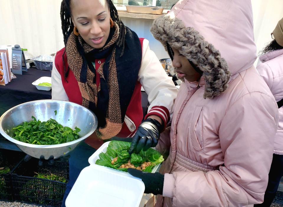 Dallas chef Amber Williams tops off a cabbage wrap with sauteed spinach for Dallas sixth-grader Madison Love, 11, at Joppy Momma's Farm in Joppa, south of Dallas on January 20, 2024. Love was among a group of suburban Dallas youngsters visiting the farm through youth leadership organization Jack and Jill of America. Joppa, a freedmen's town seven miles south of downtown Dallas, is a federally declared food desert with the nearest grocery store miles away. Williams' recently released cookbook, "Surviving the Food Desert," is aimed at families living in food deserts and/or reliant on food pantries, both of which Williams experienced herself.