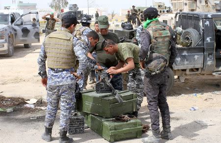 Iraqi security forces check their weapons in Tikrit March 28, 2015. REUTERS/Thaier Al-Sudani