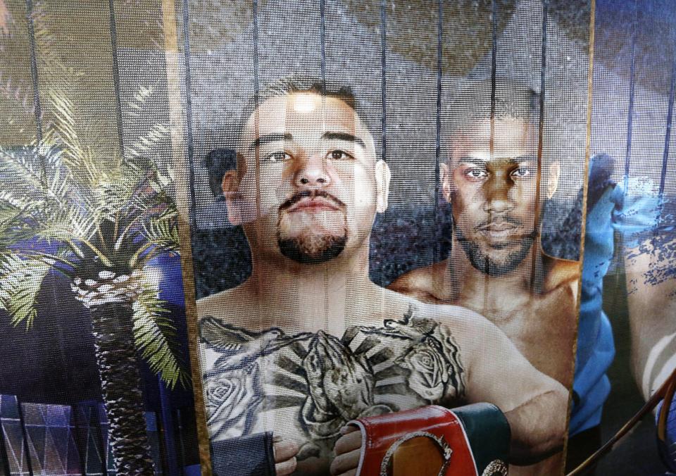 In this Saturday, Dec. 14, 2019 photo, Visitors of Diriyah a touristic site, in Riyadh, Saudi Arabia are seen through a banner showing famous boxers Andy Ruiz Jr., left, and Britain's Anthony Joshua who played in Riyadh earlier in December. "Sports has been a tool for social change within the kingdom", Prince Abdulaziz bin Turki al-Faisal, who leads the General Sports Authority, said during an interview with the Associated Press. (AP Photo/Amr Nabil)