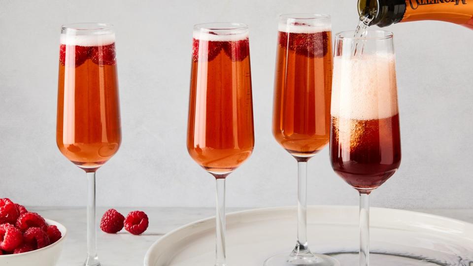three glass flutes filled with champagne, cassis liqueur, and fresh raspberries
