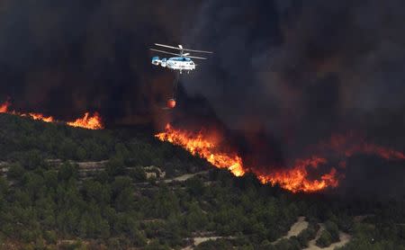 A firefighter helicopter flies over a wildfire engulfing a hillside in Benitatxell near Alicante, Spain September 5, 2016. REUTERS/Heino Kalis