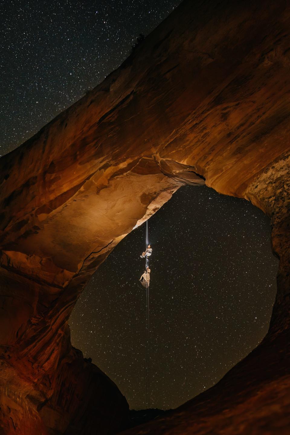 A couple rock climbing under a starry sky