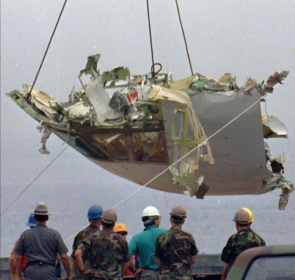 In this Aug. 7, 1996 file photo, the cockpit of TWA Flight 800 is lowered at the U.S. Coast Guard station at Shinnecock Inlet in Hampton Bays, New York. Former investigators on Wednesday, June 19, 2013 called on the National Transportation Safety Board to re-examine the cause, saying new evidence points to the often-discounted theory that a missile strike may have downed the jumbo jet.