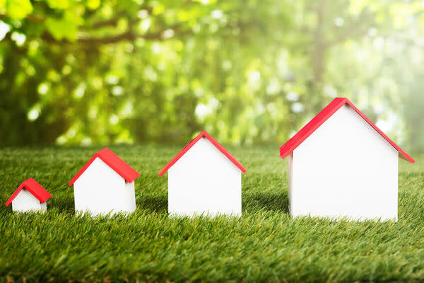 Different Size Of Houses Arranged In Row On Grassy Field