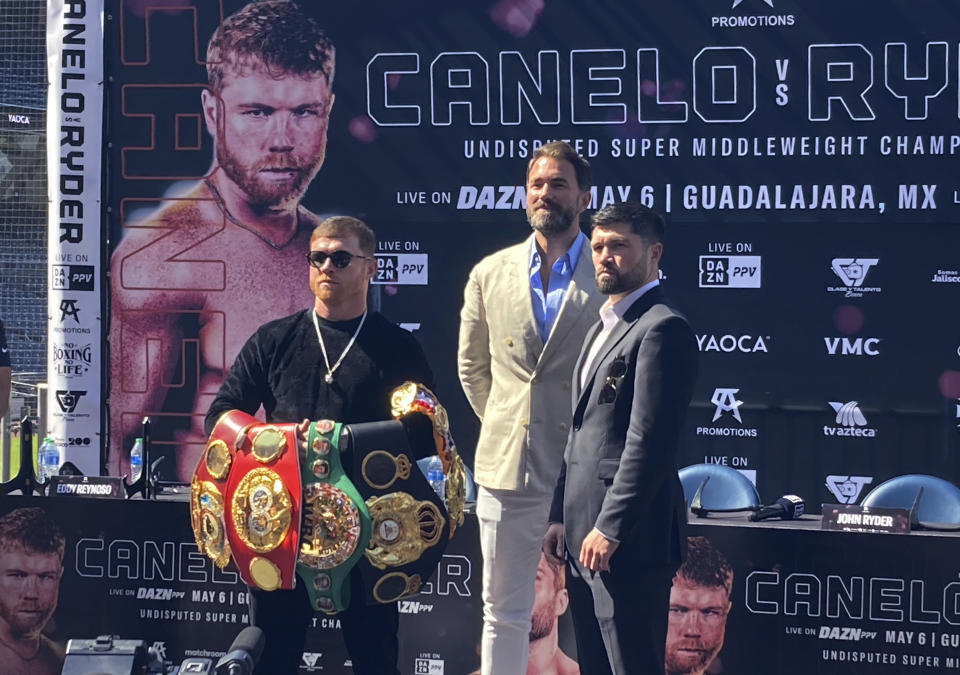 Canelo Alvarez, left, holds up his collection of super middleweight championship belts after facing off with challenger John Ryder, right, of Britain, during a news conference in San Diego on Thursday, March 16, 2023. Alvarez is taking a massive pay cut to fight in his native Mexico for the first time in 11 ½ years when he takes on Ryder on May 6. (AP Photo/Greg Beacham)