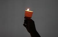 A man holds a candle during an anti-violence campaign in central Bangkok January 10, 2014. Thailand on Friday played down talk of a military coup ahead of a planned "shutdown" of the capital next week by protesters trying to overthrow Prime Minister Yingluck Shinawatra and said life would go on much as normal. REUTERS/Chaiwat Subprasom (THAILAND - Tags: POLITICS CIVIL UNREST)