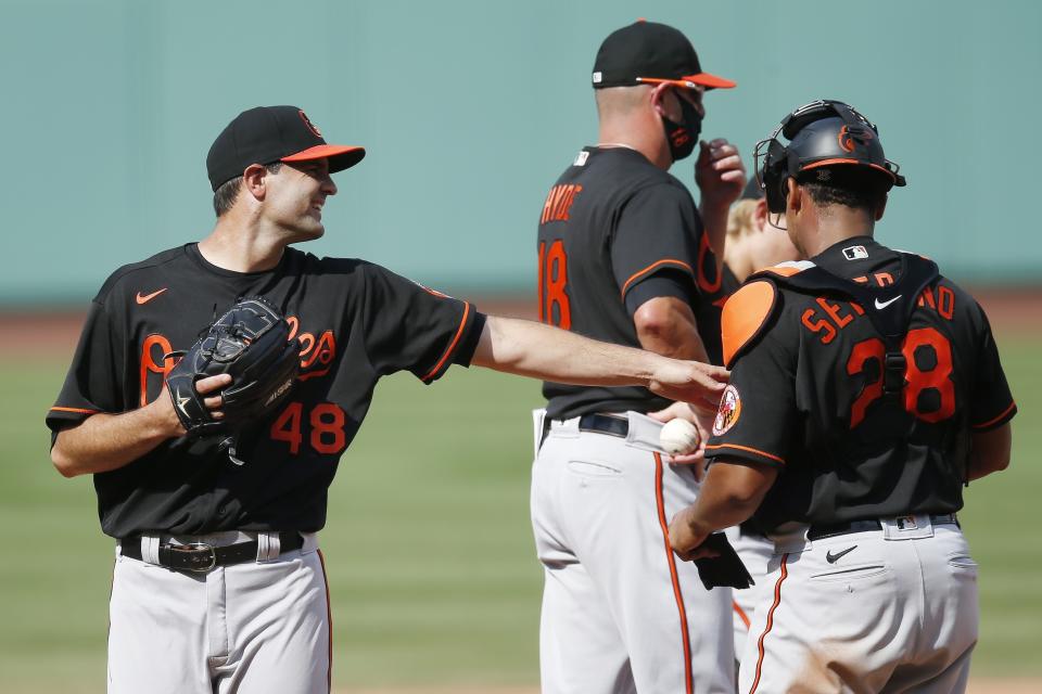 Baltimore Orioles' Richard Bleier (48) walks off the mound and reaches out to Pedro Severino (28) after being relieved by manager Brandon Hyde (18) during the eighth inning of a baseball game against the Boston Red Sox, Saturday, July 25, 2020, in Boston. (AP Photo/Michael Dwyer)