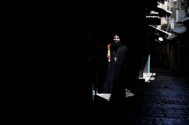 An Orthodox Christian clergyman holds candles stick after The Holy Fire ceremony just outside the Church of the Holy Sepulchre in Jerusalem's Old City amid the coronavirus disease (COVID-19) outbreak