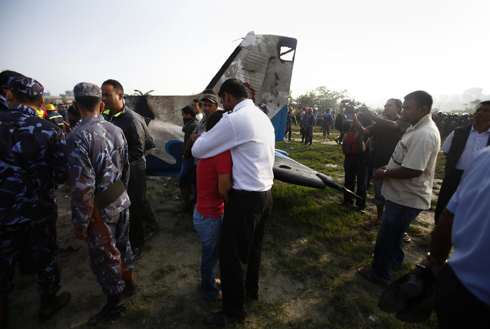 A Nepalese relative of a crew member is comforted at the crash site of a Sita Air airplane near Katmandu, Nepal, early Friday, Sept. 28, 2012.  The plane carrying trekkers into the Everest region crashed just after takeoff Friday morning in Nepal's capital, killing all 19 people on board, authorities said. (AP Photo/Niranjan Shrestha)