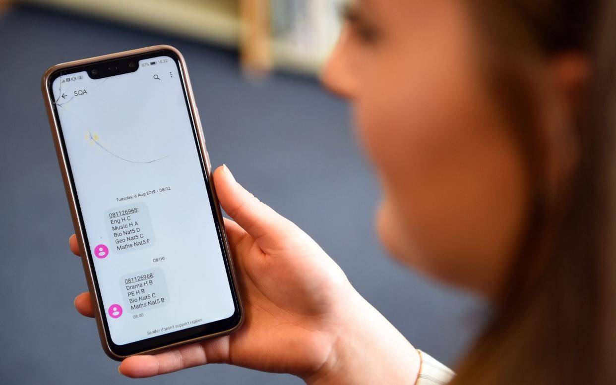 A pupil at in Glasgow receives a text message with her exam results. Exams were cancelled due to the coronavirus pandemic and pupils have been awarded grades based on assessment - Andy Buchanan/AFP