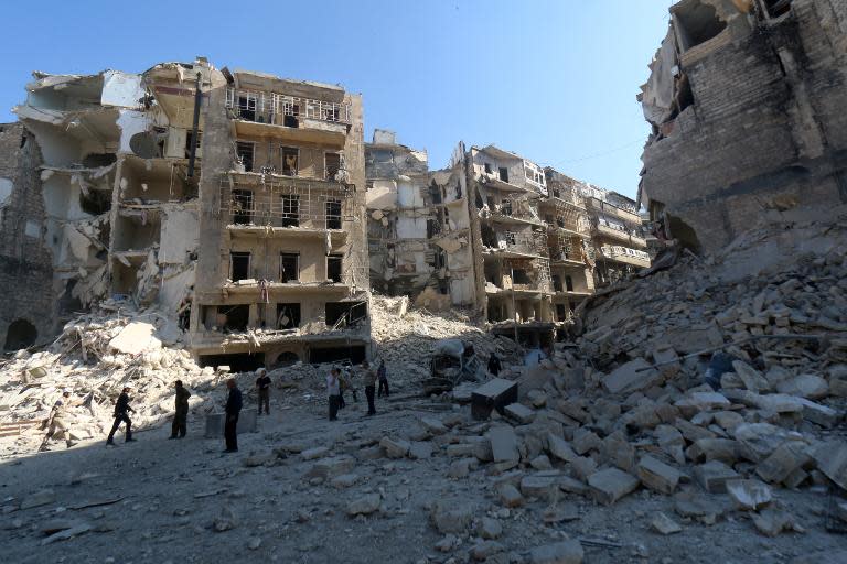 Civilians stand amid destroyed buildings in the eastern Shaar neighbourhood of the northern Syrian city of Aleppo on May 30, 2015