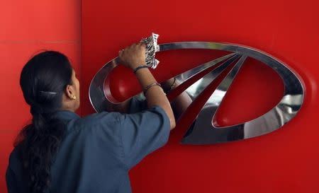 A worker cleans a logo of Mahindra & Mahindra, India's largest utility vehicles maker, inside their showroom in Chennai April 12, 2011. REUTERS/Babu/Files