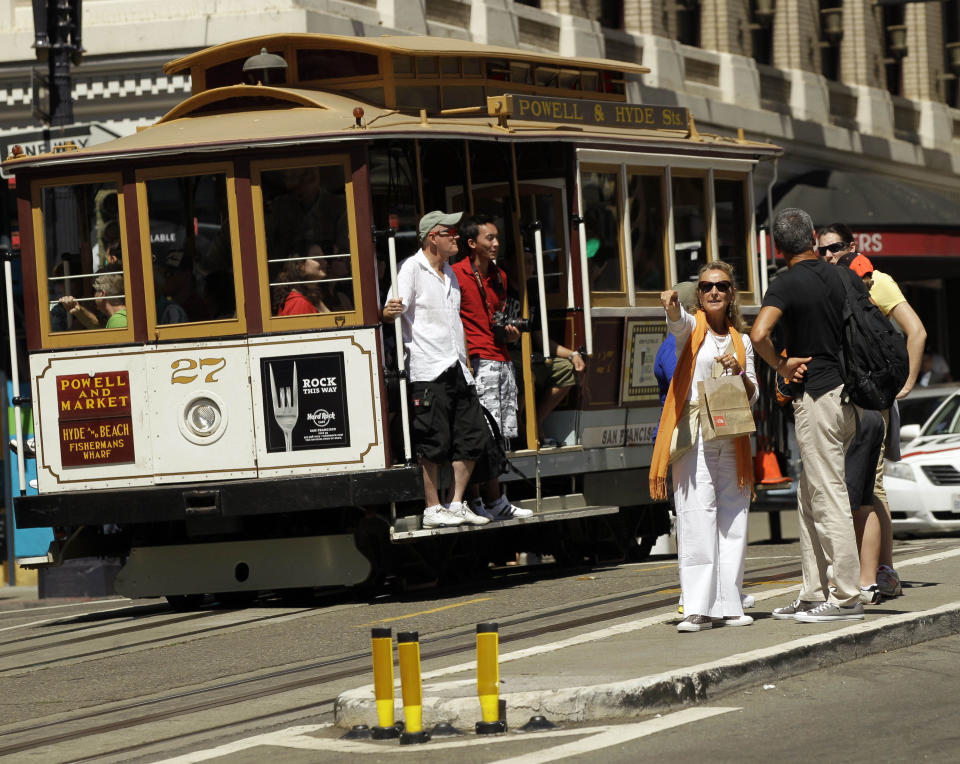 FILE - In this Sept. 1, 2010 photo, visitors wait to board a cable car in San Francisco's Union Square. In this city of innumerable tourist attractions, the clanging cable cars stand out as a top draw. They also stand out for the inordinate number of accidents and the millions of dollars annually the city pays out to settle lawsuits for broken bones, severed feet and bad bruises caused when 19th Century technology runs headlong into 21st Century city traffic and congestion. Recently, five passengers and two workers were injured after an inch-long bolt in the track caused their cable car to slam to a sudden stop. (AP Photo/Marcio Jose Sanchez)