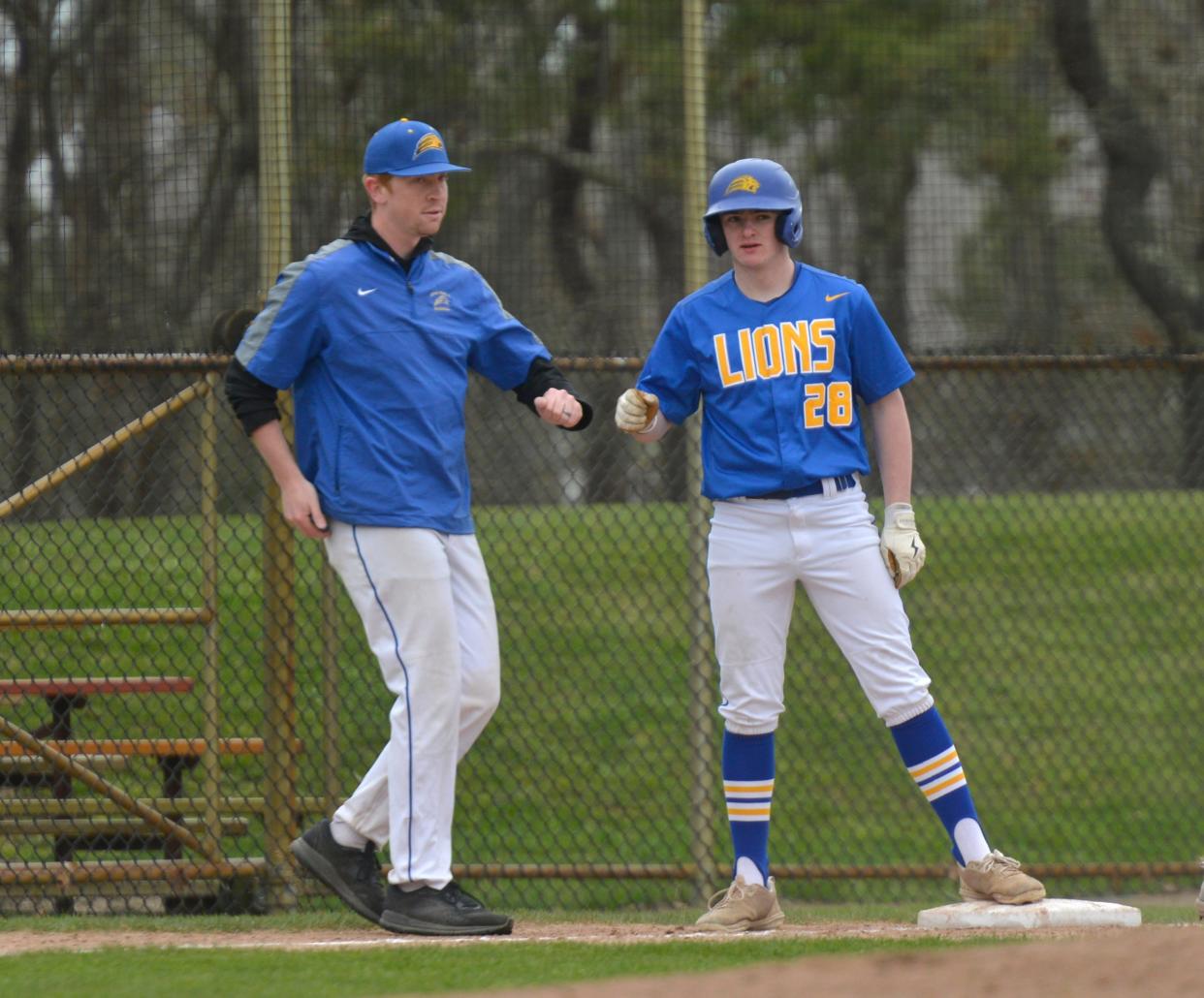 St. John Paul II coach Michael Young, left, fist bumps with player Colin Buckley who made it to third base in first inning action.