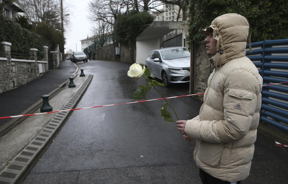 A youth holds a white rose at the entrance of a private Catholic school after a teacher of Spanish has been stabbed to death by a high school student, Wednesday, Feb. 22, 2023 in Saint-Jean-de-Luz, southwestern France. The student has been arrested by police, the prosecutor of Bayonne said. (AP Photo/Bob Edme)