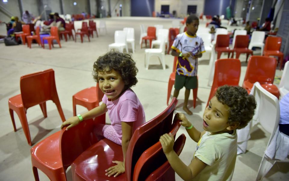 Local children play in the safety of a temporary cyclone shelter in the town of Ayr in far north Queensland - Credit:  AFP