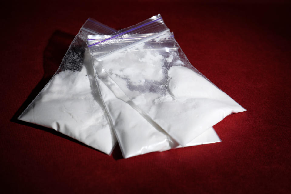 Cocaine in plastic bags on color background