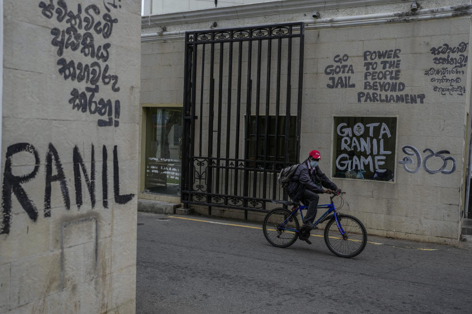 A man pedals past vandalized walls of the official residence of the president the day after Ranil Wickremesinghe was elected president in Colombo, Sri Lanka, Thursday, July 21, 2022. Sri Lanka's prime minister was elected president Wednesday by lawmakers who opted for a seasoned, veteran leader to lead the country out of economic collapse, despite widespread public opposition. (AP Photo/Rafiq Maqbool)