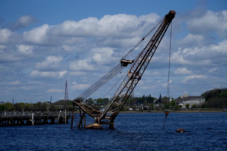 A crane, on a sunken barge in the waters at the end of Public St. in Providence, sticks up through the water on April 24, 2023. 
