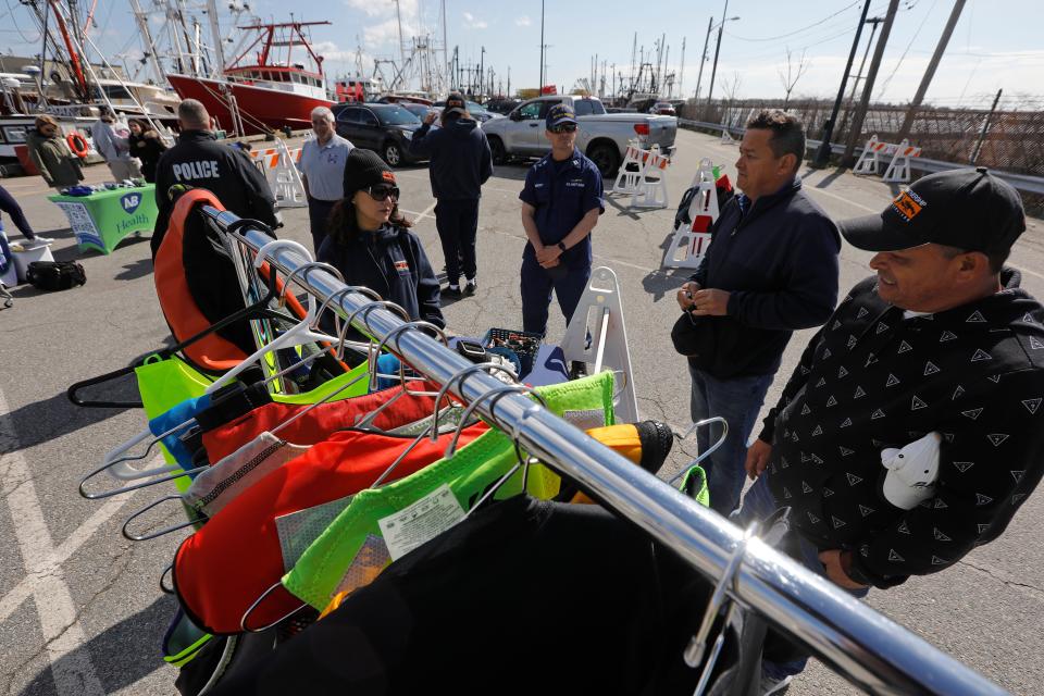 Two fishermen meet with Waterfront Partnership Support Services about some of the programs they have including life vests, at a free health and wellness event hosted by the Greater New Bedford Waterfront Task Force on Leonard's Wharf in New Bedford.