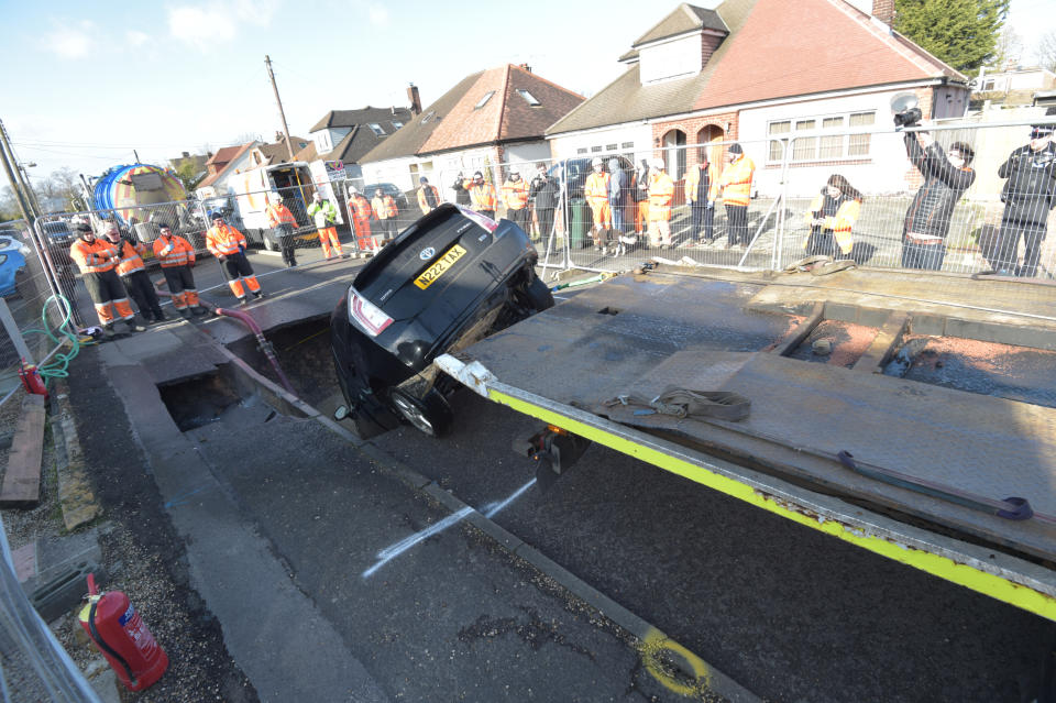 A Toyota car is removed from a sinkhole which appeared overnight in Hatch Road, Brentwood, in the aftermath of Storm Ciara, which hit the country Sunday.