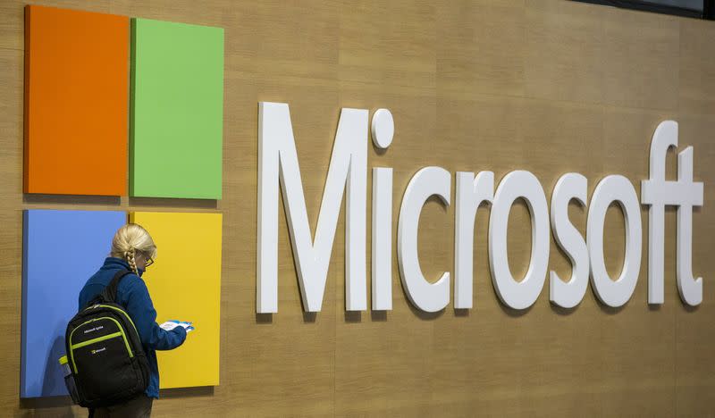 An attendee at the Microsoft Ignite technology conference is seen next to the Microsoft logo in Chicago, Illinois, May 4, 2015. REUTERS/Jim Young