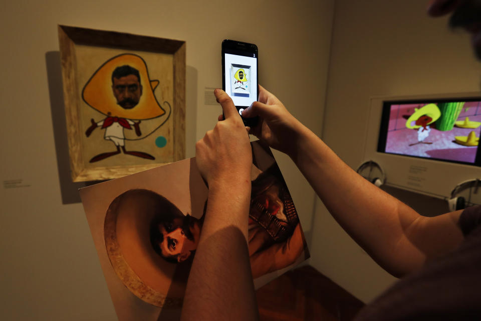 Un periodista toma una fotografía de una pintura con el cuerpo de la caricatura Speedy Gonzalez y el rostro del revolucionario mexicano Emiliano Zapata en la exposición “Emiliano. Zapata después de Zapata” del Museo del Palacio de Bellas Artes en la Ciudad de México el martes 26 de noviembre de 2019. La muestra incluye 140 obras y objetos relacionados con Zapata. (Foto AP/Marco Ugarte)