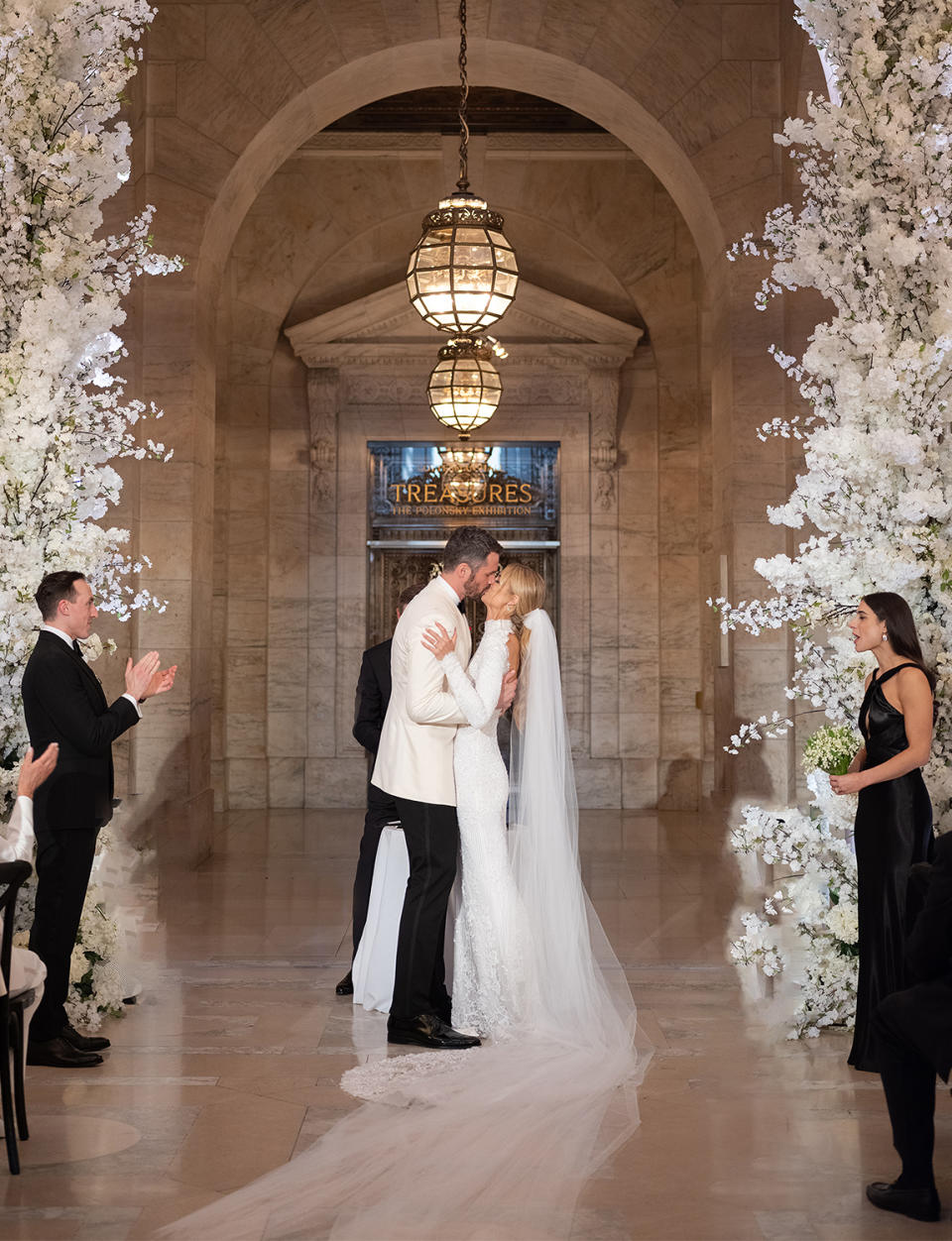 <p>The couple makes it official under a white cherry blossom chuppah designed to match the arches of the library. </p>