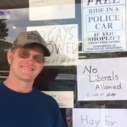 Jeff Amyx poses next to the door of his hardware store with signs that read “No Gays Allowed” and “No Liberals Allowed.” (Photo: Facebook)