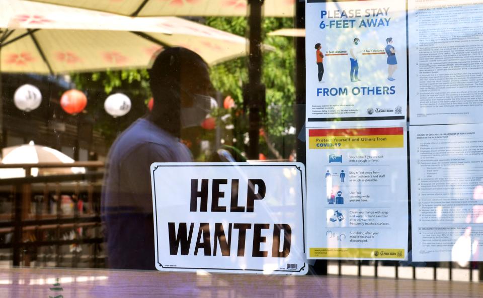 A 'Help Wanted' sign and coronavirus safety guidelines are posted in a window.