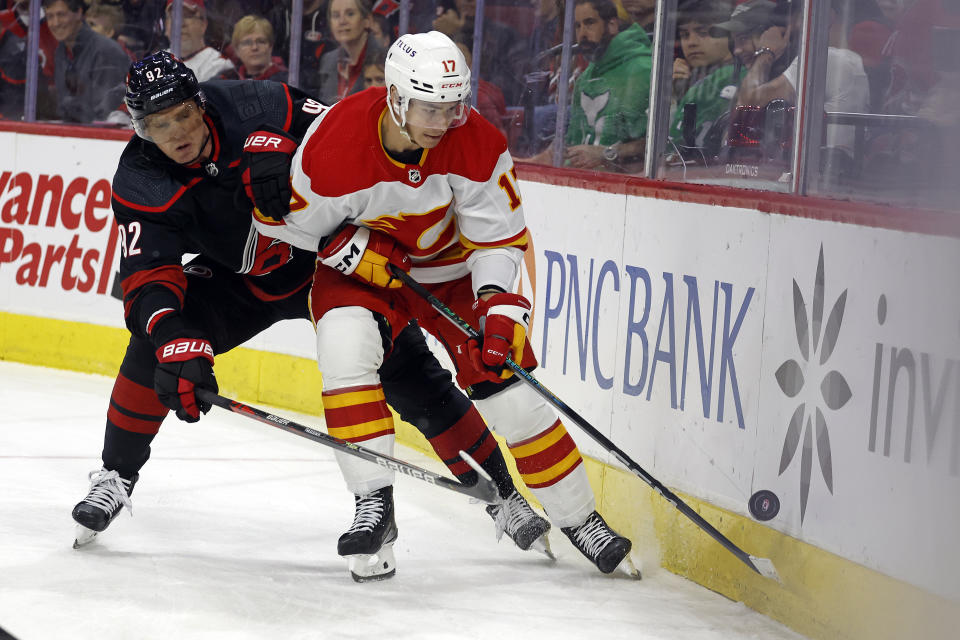 Calgary Flames' Yegor Sharangovich (17) protect the puck from Carolina Hurricanes' Evgeny Kuznetsov (92) during the first period of an NHL hockey game in Raleigh, N.C., Sunday, March 10, 2024. (AP Photo/Karl B DeBlaker)