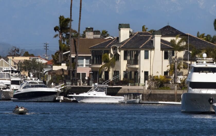 HUNTINGTON BEACH, CA. --FEBRUARY 20, 2013: A California brown pelican soars as a motor boater cruises Huntington Harbor. (Allen J. Schaben/Los Angeles Times)