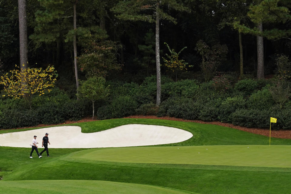 Rory McIlroy, of Northern Ireland, walks with Phil Mickelson on the 13th fairway during a practice round for the Masters golf tournament Tuesday, Nov. 10, 2020, in Augusta, Ga. (AP Photo/Matt Slocum)