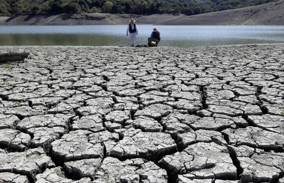 FILE - This Thursday, March 13, 2014 file photo shows cracks in the dry bed of the Stevens Creek Reservoir in Cupertino, Calif. A study is asserting a link between climate change and both the intensifying California drought and the polar vortex blamed for a harsh 2013-2014 winter that has just ended in many places. The Utah State University scientists involved in the study say they hope what they found can help them predict the next big weird winter. (AP Photo/Marcio Jose Sanchez)