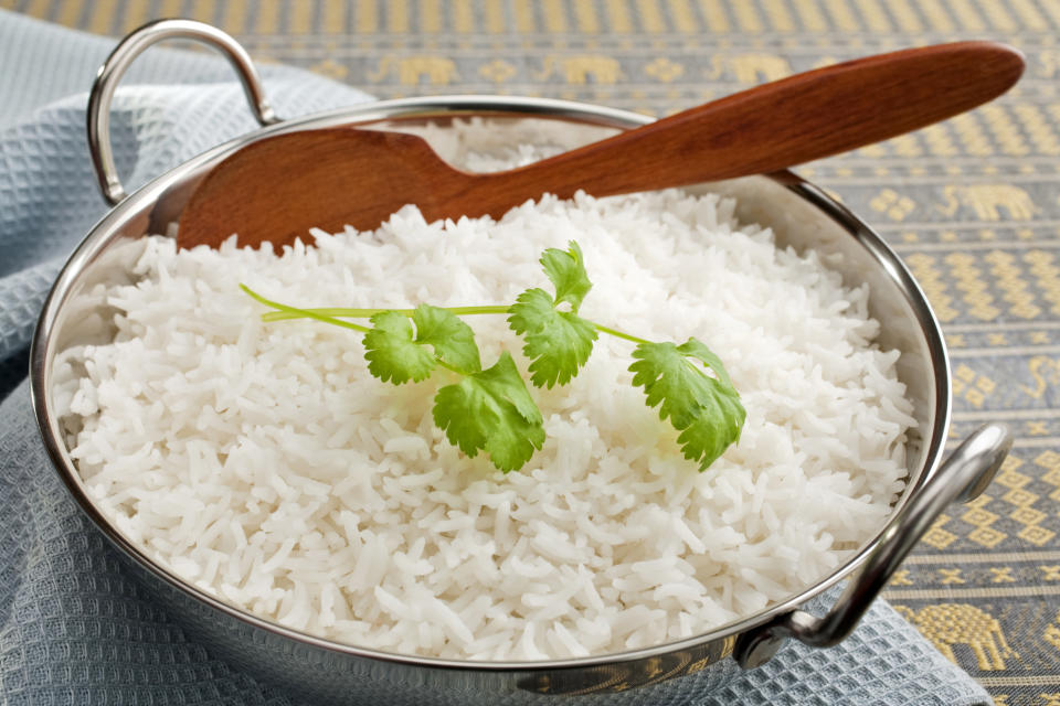 Basmati rice in a steel karahi, garnished with coriander,with a wooden spoon.