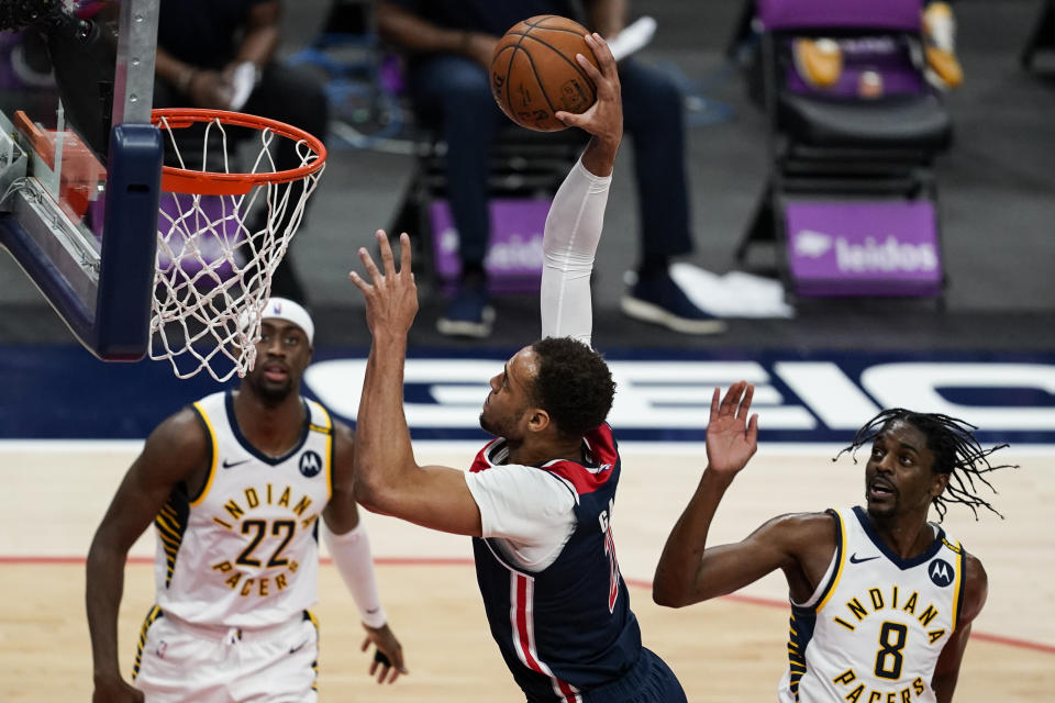Washington Wizards forward Daniel Gafford (21) dunks the ball in front of Indiana Pacers guards Caris LeVert (22) and Justin Holiday (8) during the first half of a basketball game, Monday, May 3, 2021, in Washington. (AP Photo/Alex Brandon)